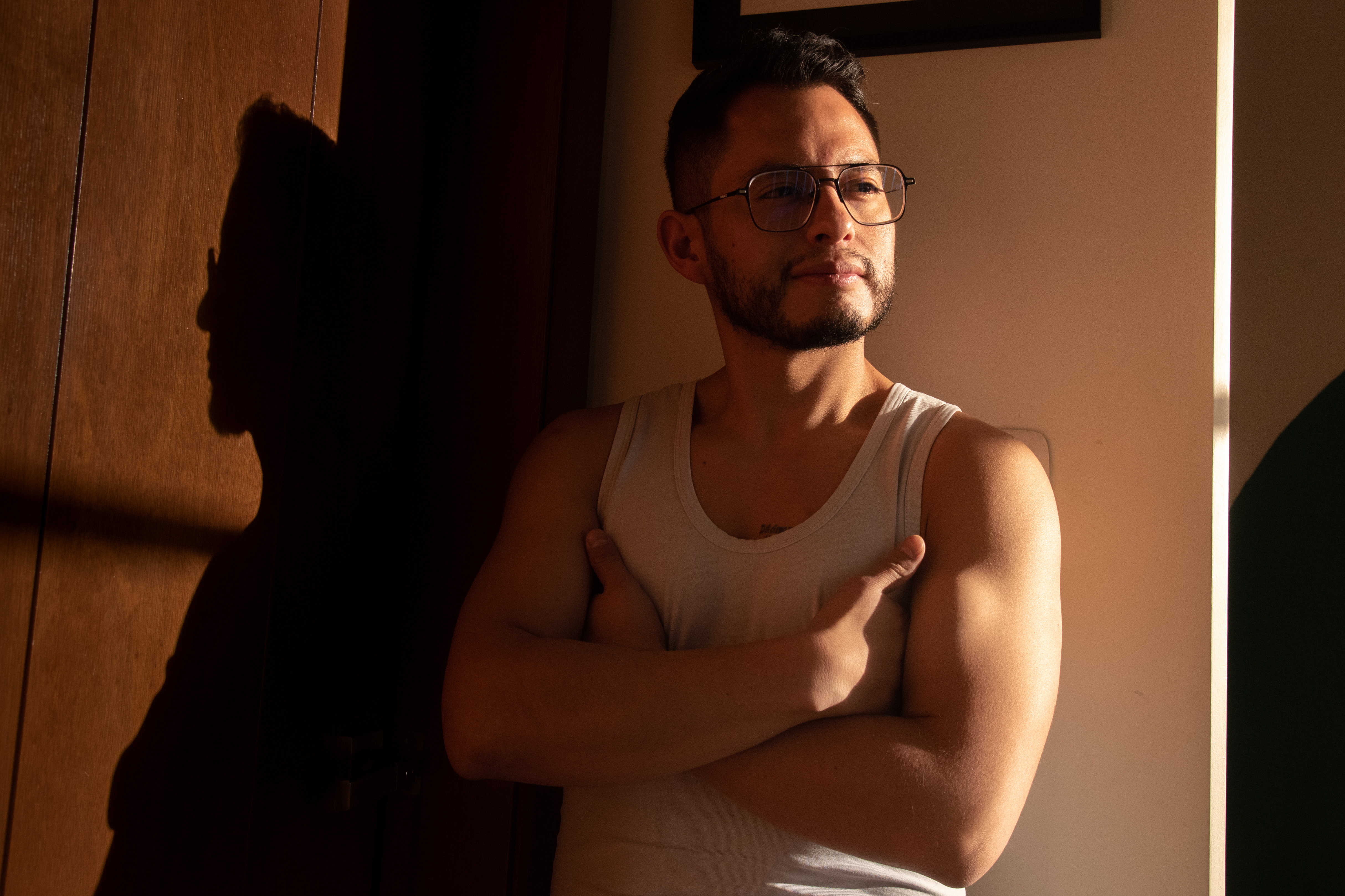Retrato de Juan Pablo Vargas Rollano junto a una sombra proyectada por la luz de la tarde.